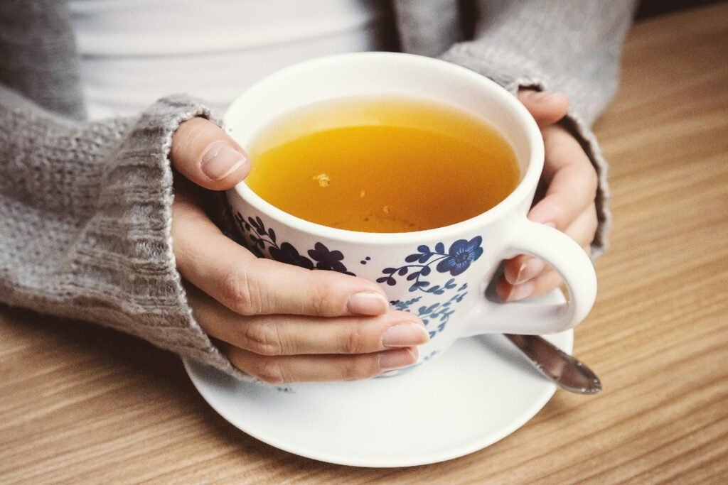 Cup of Manuka Honey Tea with hands wrapped around tea cup.